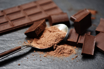 chocolate bar and chocolate powder on spoon on the dark background - chunks candy sweet dessert and snack