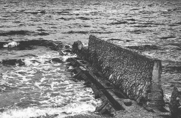 The sea wave. White foamy waves bounce against the stones.