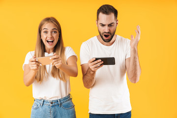 Image of emotional couple playing video games on smartphones together