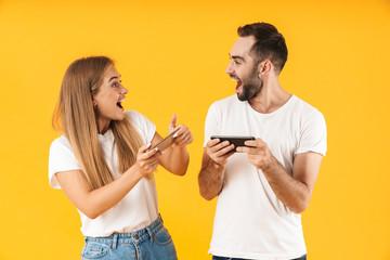 Image of cheerful couple playing video games on smartphones together