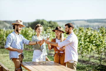 Group of young friends dressed casually having fun together, tasting wine on the vineyard on a...