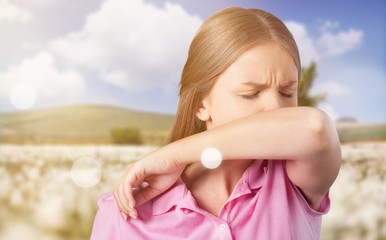 Young woman scratching her nose with elbow on dark gray background