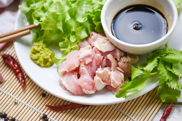 Sashimi raw chicken on white plate with wasabi sauce and vegetable salad garlic chilli herbs and spices traditional japanese food - chicken slices meat fillet
