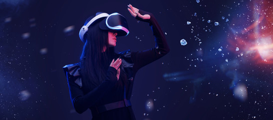 Obraz na płótnie Canvas Beautiful woman with flowing hair in futuristic dress over dark magic light background. Girl in glasses of virtual reality. Augmented reality, game, future technology concept. VR.