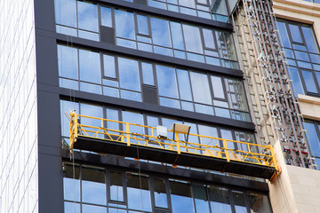 Construction cradle on the facade of the building under construction of a high-rise building. Horizontal.