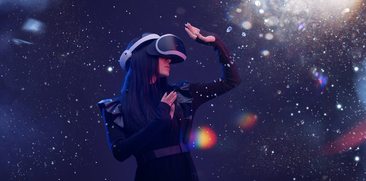 Beautiful woman with flowing hair in futuristic dress over dark magic light background. Girl in glasses of virtual reality. Augmented reality, game, future technology concept. VR. © KDdesignphoto