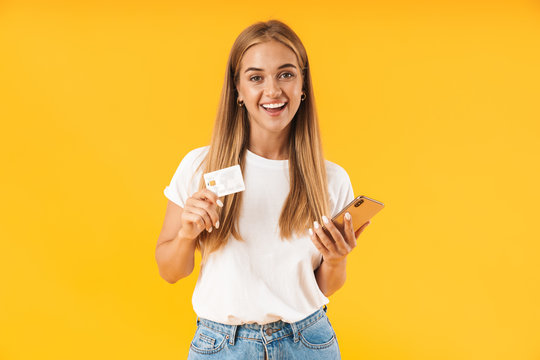 Image of cute woman smiling while holding smartphone and credit card