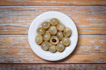 Longan fresh tropical fruit in Thailand - Dimocarpus longan peel exotic fruits on white plate on wooden background , top view