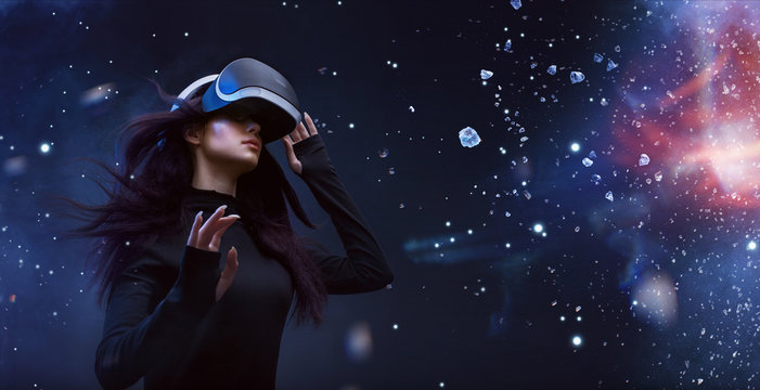 Beautiful woman with flowing hair in futuristic dress over dark magic light background. Girl in glasses of virtual reality. Augmented reality, game, future technology concept. VR.