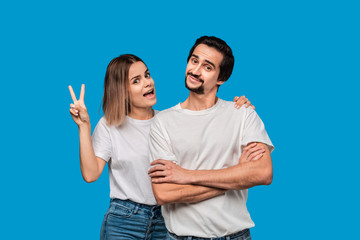 Happy couple of a young blond woman and brunet bearded man with mustaches in white t-shirts and...