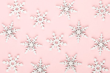 Christmas background. White snow decorations on a pink background.