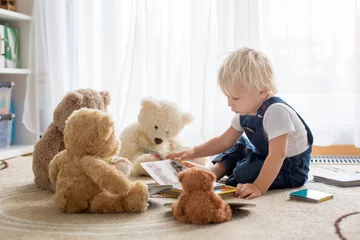 Fotobehang Little toddler boy, reading a book to his teddy bear friends at home © Tomsickova