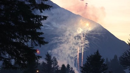 Fireworks at Dusk With Mountain in Background and Silhouetted Trees in Foreground