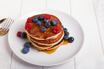 Stack of delicious homemade pankes with berries on the white plate