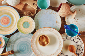 Top view of assorted colorful ceramic plates and kitchen utensils 