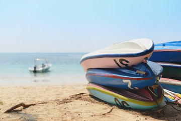 Obraz premium Kayaks stacked on sand beach in front of boat in the sea. Vacation and travel sport activity. Free copy space.