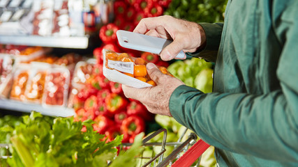 Kunde scannt Packung Lebensmittel mit Smartphone
