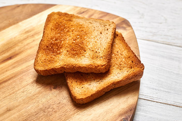 Toasted white bread toasts on a wooden background.