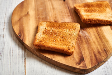 Toasted white bread toasts on a wooden background.