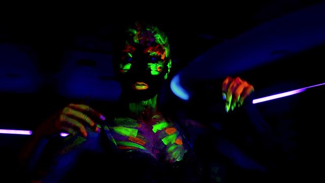 Beautiful young sexy girl dancing with ultraviolet paint on her body. Girl with neon bodyart