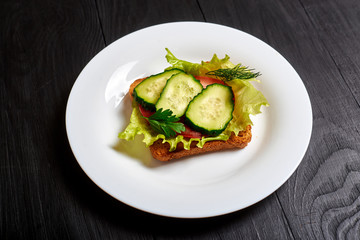 Sandwich with fresh vegetables, vegetarian. Salad, cucumbers, tomato on toasted toast.