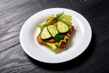 Sandwich with fresh vegetables, vegetarian. Salad, cucumbers, tomato on toasted toast.