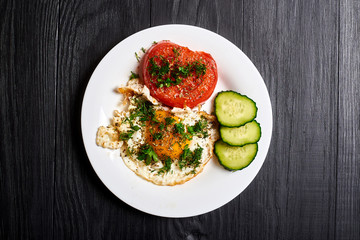 Grilled egg and grilled tomato on a plate on a wooden background. Fast and easy to prepare breakfast.