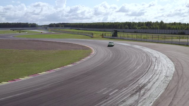 Aerial view sport car racing on speed drift track. Rear wheel drive jdm car drifting on turn on racing track. Drone view driver riding on racing track