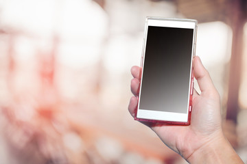 Smartphone in hand with bokeh background and black empty screen.
