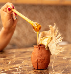 Honey in clay pots on a wooden spoon