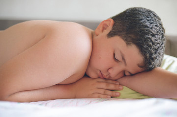 Fototapeta na wymiar cute fat little caucasian kid with eyes closed lying in bed on pillow deep sleeping in morning