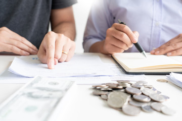 couple working saving account book and calculating her monthly expenses on calculator to calculate...