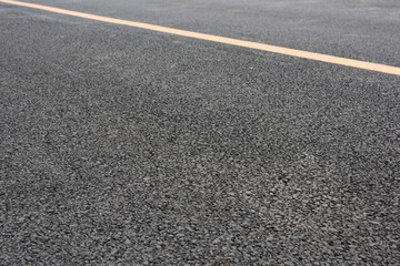 Fototapeta premium Low angle close-up of wide asphalt road and yellow paint line