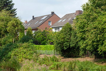 Fototapeta na wymiar Wohnhäuser, Einfamilienhäuser im Grünen an einem Dewässer, Bremen, Deutschland