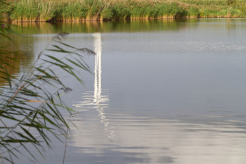 Windmühle spiegelt sich im Angelgewässer in Nordfriesland