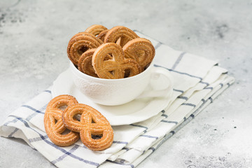 Cookies in the form of pretzels in a white Cup on a light gray table