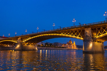 The Margaret Bridge with Parliament Building on background in Budapest, Hungary, illuminated above...