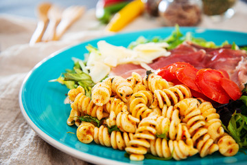 Salad made with cooked pasta, mixed green salads, cherry tomatoes, Mozzarella cheese and smoked ham served with accompaniment