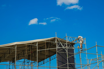 stage construction process with worker, blue sky background, copy space 