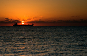 Naklejka na ściany i meble Sunrise at the Fort Lauderdale beach near Miami in Florida with sun coming out from behind a ship