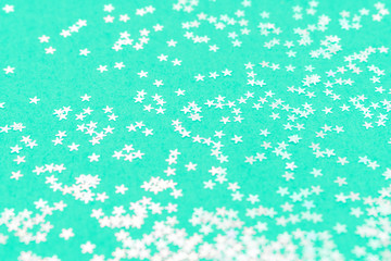 Trendy green mint background with metallic stars. Christmas backdrop. Selective focus.