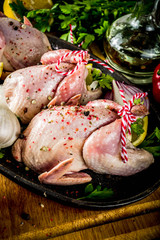 Cooking healthy diet lunch concept. Three whole quails with spices, herbs, vegetables, olive oil, for cooking on a black stone concrete table copy space