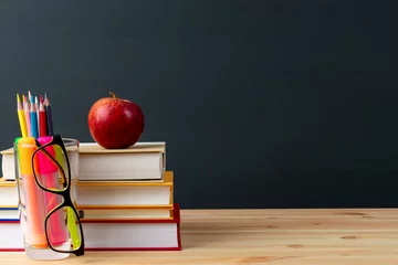 World teacher day - apple and books with pencils and eyeglasses on table in classroom. © Phongsakorn