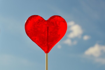 Heart shaped lollipop against blue sky