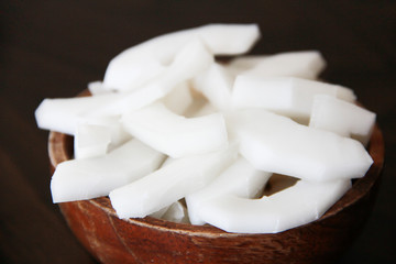 slices of chopped white natural tasty coconut in a brown wooden plate