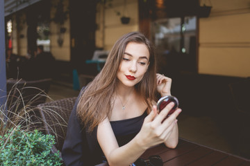 Elegant woman looking in the mirror while sitting at a table in a restaurant