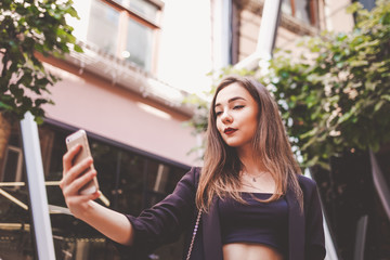 Fototapeta na wymiar stylish young girl takes a selfie. girl makes her photo on smartphone.
