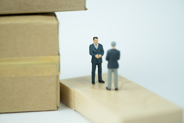 Miniature people figures standing, talking and hand shake with brown box.