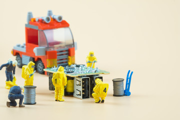 Tiny figures of chemical team in hazmat suits examining