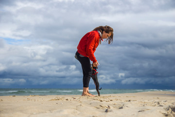 Młoda dziewczyna bawi się z pieskiem pinczerem miniaturowym ratler na plaży nad morzem